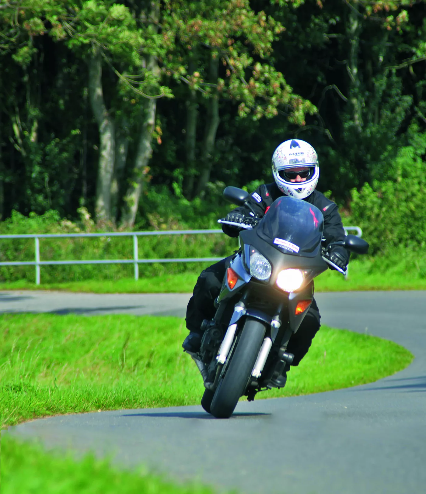 Motorrad in einer Kurve auf einer Landstraße zwischen Wiesen